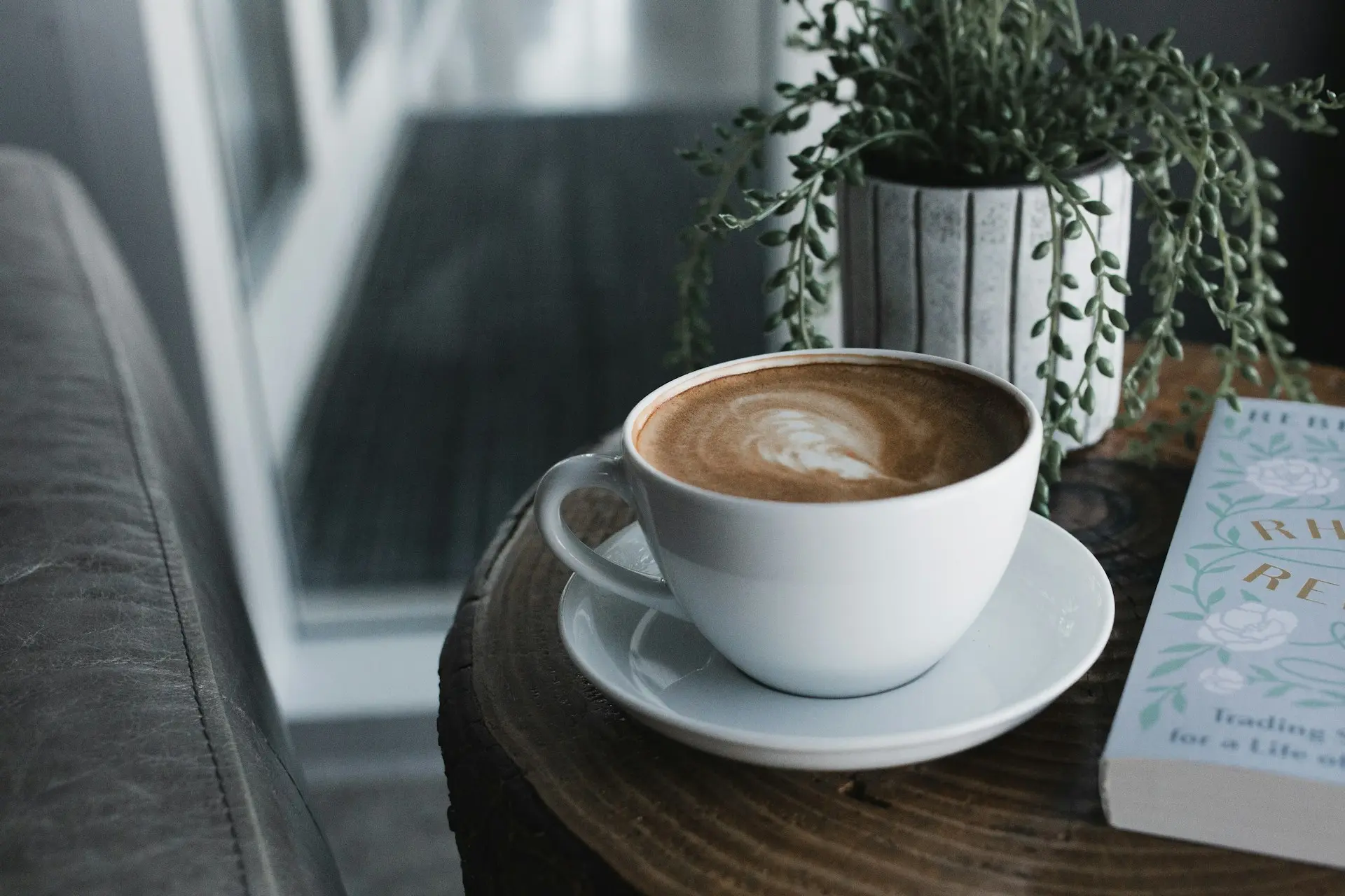 A professional flat lay of the coffee-making process on a dark wooden surface, featuring roasted beans, ground coffee in a portafilter, and a finished latte with heart-shaped foam art.